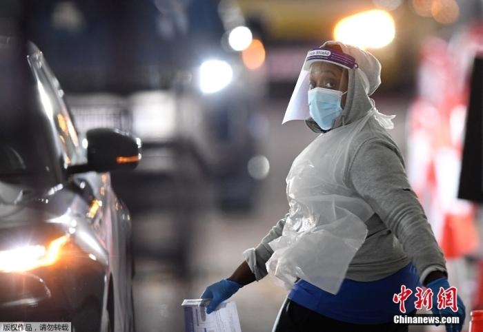 當?shù)貢r間12月18日，英國政府公布的數(shù)據(jù)顯示，當天英國新增奧密克戎毒株感染病例10059例。鑒于奧密克戎毒株感染病例激增，住院人數(shù)不斷上升，倫敦市長宣布倫敦進入“重大事故”狀態(tài)。圖為倫敦的一個免下車檢測中心，一名醫(yī)務工作者正準備對司機進行核酸檢測。