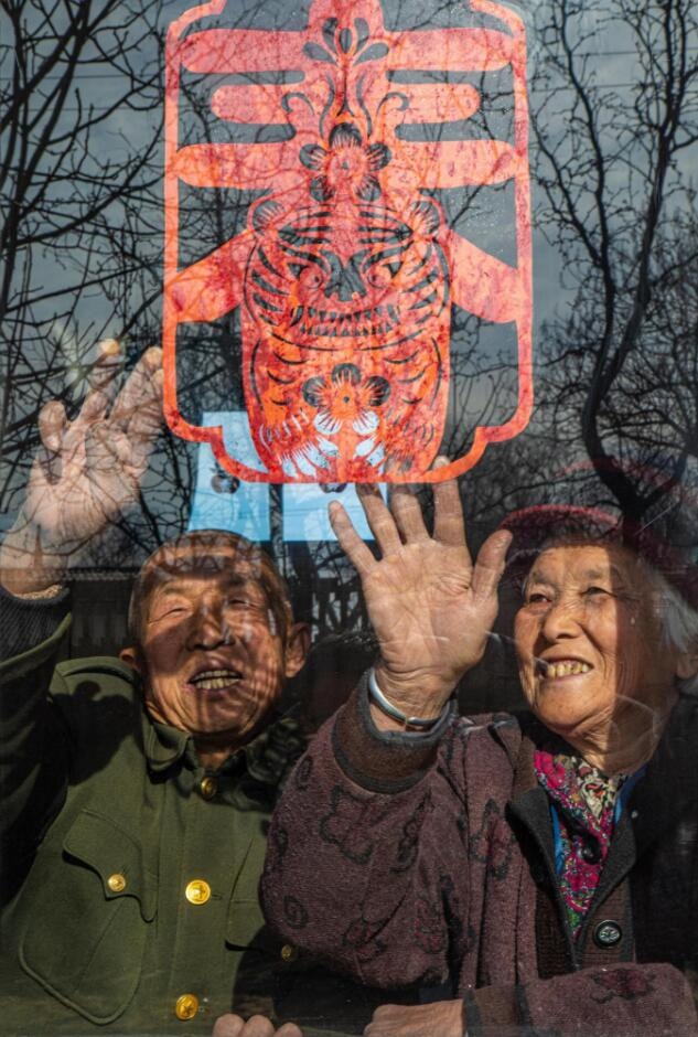 臘月里，霍州市師莊鄉(xiāng)馮南垣村村民師榮光(左)在災(zāi)后重建的新家里貼窗花。(霍州市委宣傳部供圖)