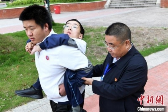 朱金祥背著鐘華強(qiáng)去教室上課的路上，也經(jīng)常碰到值班的校領(lǐng)導(dǎo)和老師前來搭把手。 卓忠偉 攝