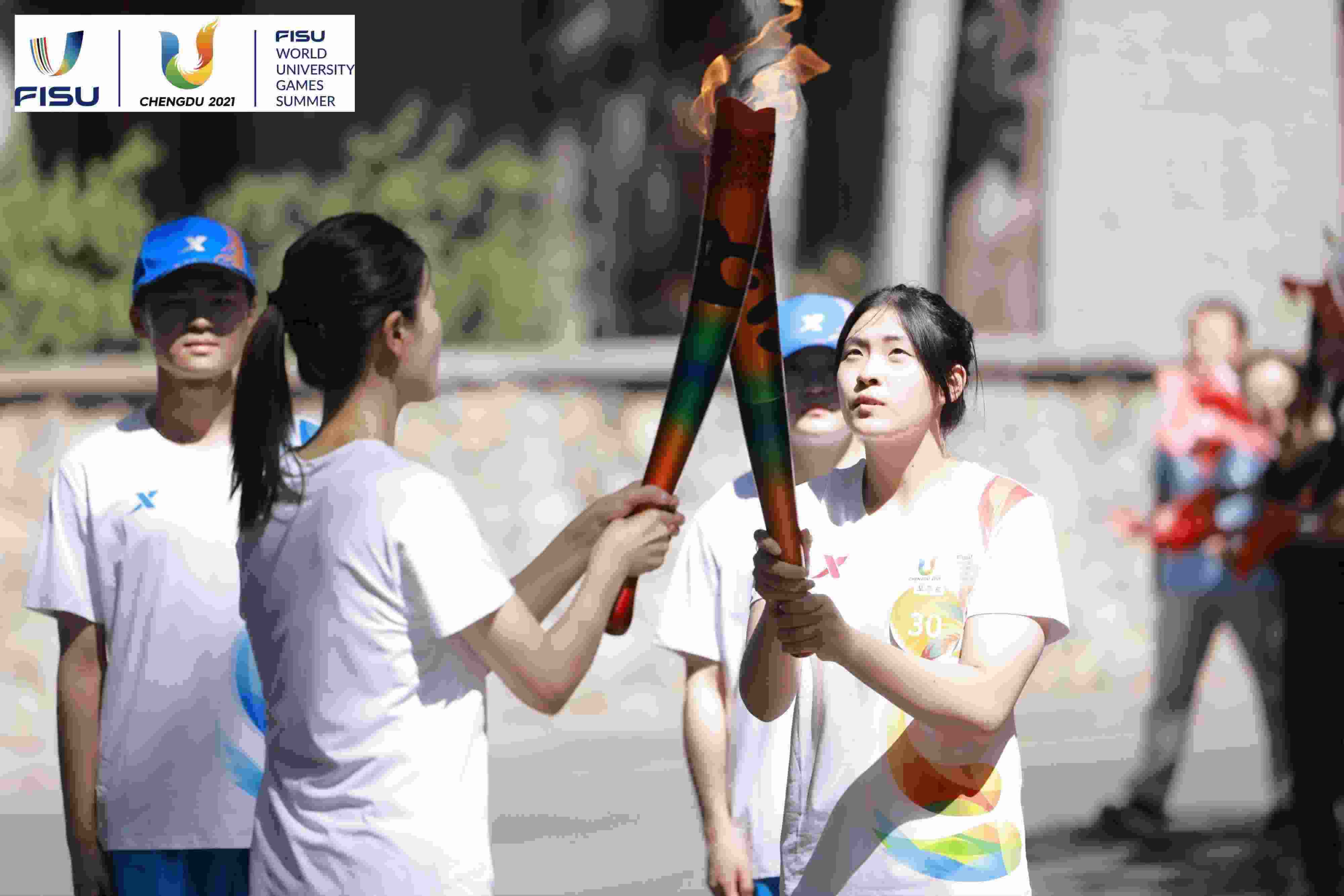 兩名大運(yùn)會(huì)火炬手進(jìn)行火炬?zhèn)鬟f。 圖片來(lái)源：成都大運(yùn)會(huì)執(zhí)委會(huì)供圖