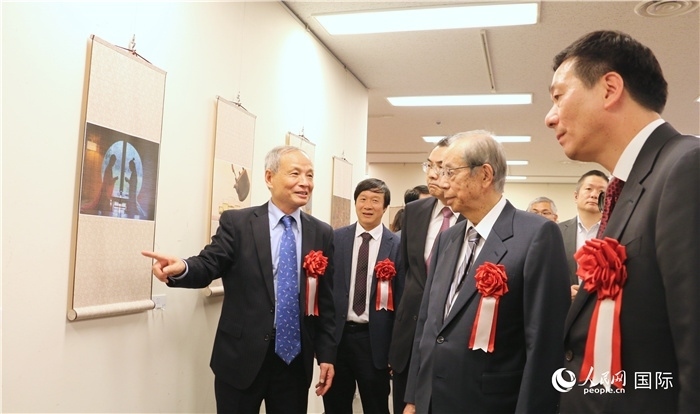 “湖州印象”攝影展主創(chuàng)、世界華人攝影協(xié)會(huì)副會(huì)長(zhǎng)馮學(xué)敏向吳江浩大使、福田康夫前首相等嘉賓介紹展出作品。（人民網(wǎng) 許可攝）