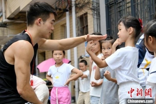 圖為大學生志愿者在組織孩子們參加體育健身活動。廖光福 攝