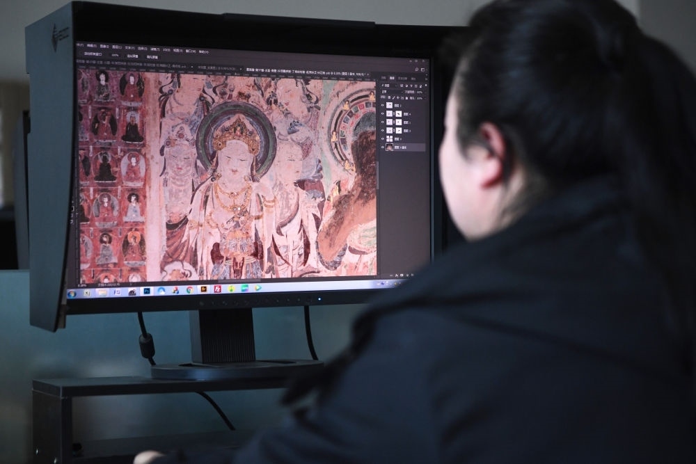 敦煌研究院文物數(shù)字化保護(hù)團(tuán)隊(duì)圖像處理人員年海麗在拼接壁畫圖像（2023年4月25日攝）。數(shù)字化探索為莫高窟的保護(hù)與傳承開辟了全新路徑，數(shù)字技術(shù)讓敦煌文物走出洞窟，跨出國(guó)門，走向“永久保存、永續(xù)利用”。新華社記者 陳斌 攝