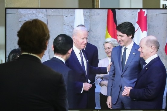 2022年3月24日，在比利時(shí)布魯塞爾的北約總部，一名男子觀看屏幕上美國(guó)總統(tǒng)拜登（右四）、歐盟委員會(huì)主席馮德萊恩（右三）、加拿大總理特魯多（右二）、德國(guó)總理朔爾茨（右一）出席七國(guó)集團(tuán)峰會(huì)合影儀式的畫(huà)面。新華社記者鄭煥松攝