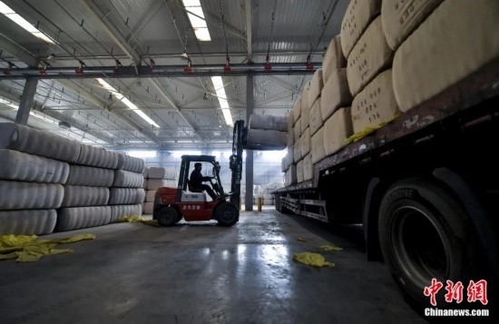 新疆喀什綜合保稅區(qū)，喀什啟路國際貿(mào)易有限公司的倉庫內(nèi)，工人正在裝載從塔吉克斯坦和烏茲別克斯坦進(jìn)口的棉花。劉新攝