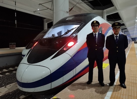 劉銀能（右一）與中國師父鄔俊鴻在動車組前合影。受訪者供圖