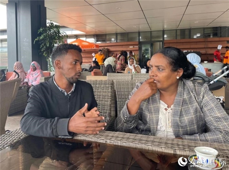 約漢斯（圖左）與德貝拉在友誼廣場咖啡廳交談。人民網(wǎng)記者 趙艷紅攝