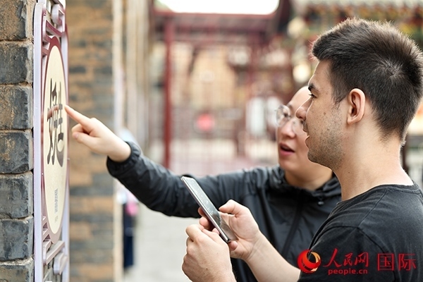 選手安德烈（俄羅斯）在老師指導(dǎo)下學(xué)習(xí)墻壁上張貼的生僻字。人民網(wǎng) 盧鵬宇攝