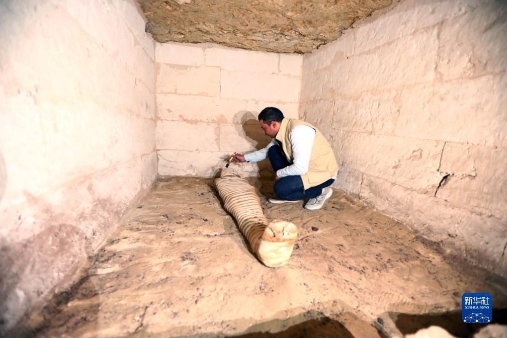 10月15日，在埃及明亞省考古現(xiàn)場，考古人員清理一座石鑿墓中的木乃伊。新華社發(fā)（艾哈邁德·戈馬攝）