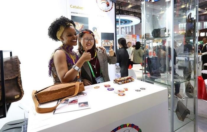 11月6日，一位參觀者（右）在第六屆進博會國家展南非展臺試戴傳統(tǒng)首飾。