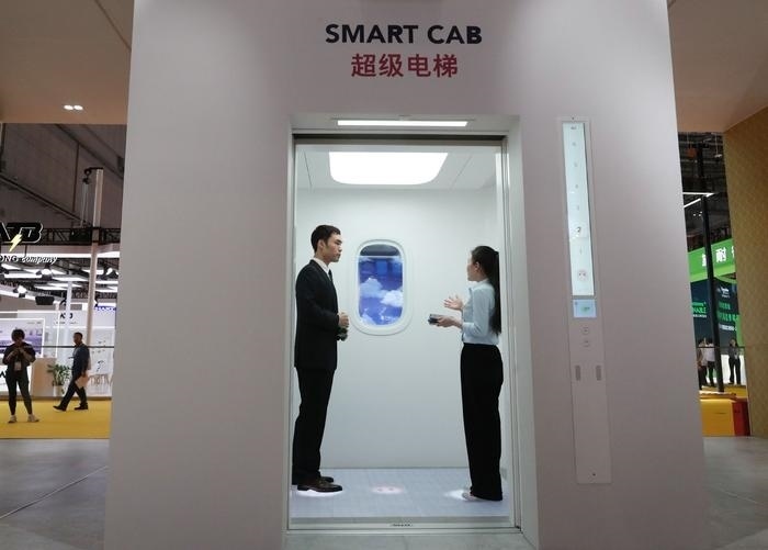 11月5日，工作人員（右）在第六屆進博會上向參觀者介紹奧的斯公司全新推出的超級電梯。