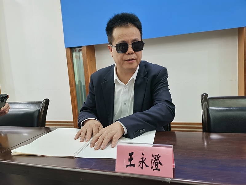 全國(guó)人大代表王永澄正在閱讀盲文版代表建議答復(fù)。本報(bào)記者 張 璁?dāng)z