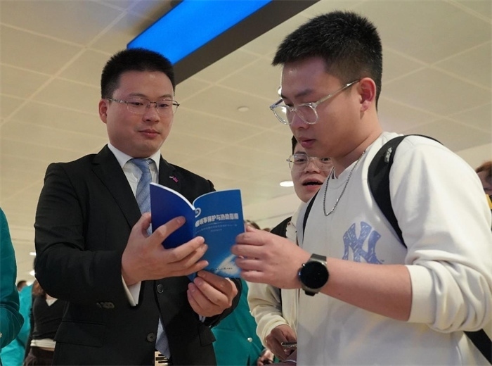 工作人員（左一）在發(fā)放《中國(guó)領(lǐng)事保護(hù)與協(xié)助指南》。 中國(guó)駐迪拜總領(lǐng)事館供圖