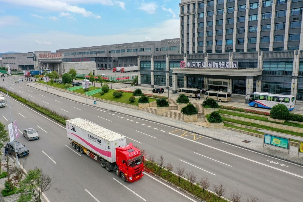 2023年10月11日，滿載筆記本電腦配件、發(fā)電機(jī)組件等產(chǎn)品的西部陸海新通道跨境公路班車從重慶南彭公路保稅物流中心駛出，將途經(jīng)廣西憑祥，直達(dá)越南（無人機(jī)照片）。新華社記者 黃偉 攝