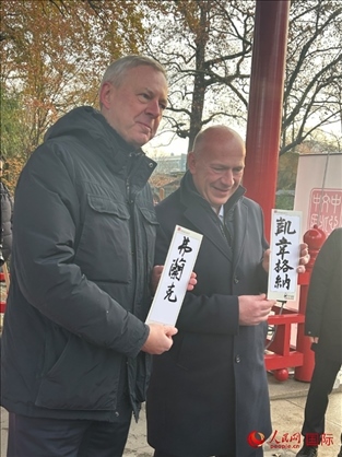 柏林市長韋格納（右）、動(dòng)物園監(jiān)事會主席布魯克曼（左）手持中國文化中心工作人員現(xiàn)場手書的中文名字。人民網(wǎng)記者 徐馨攝