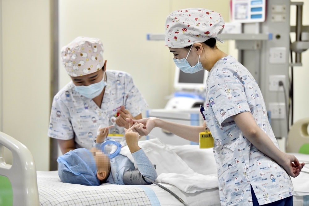 在山東省棗莊市婦幼保健院兒童ICU病房，醫(yī)護人員為完成靶向治療藥物諾西那生鈉的4歲脊髓性肌萎縮癥患兒加油鼓勁（2022年1月1日攝）。諾西那生鈉注射液是我國首個獲批治療脊髓性肌萎縮癥的進口藥物，2019年進入中國市場時，每針價格近70萬元。在2021年國家醫(yī)保目錄藥品談判中，以3.3萬元每針的價格進入新版醫(yī)保藥品目錄。新華社記者 郭緒雷 攝