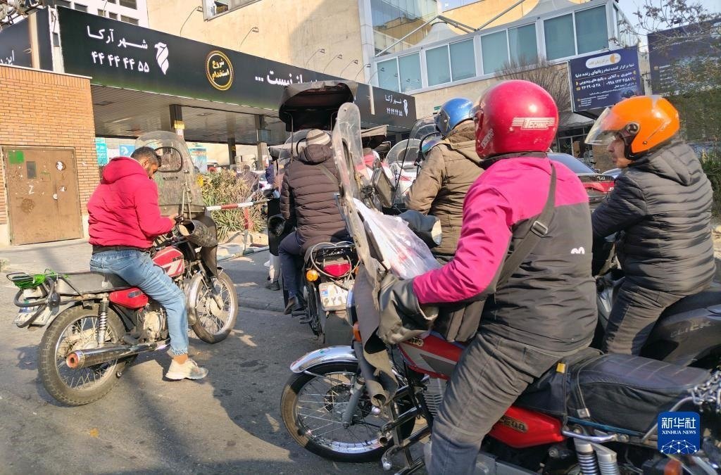 12月18日，摩托車在伊朗首都德黑蘭的一家加油站外等待加油。新華社記者 沙達提 攝