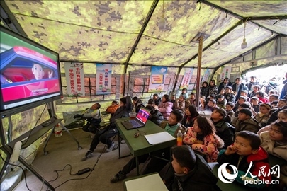 12月22日，在積石山縣大河家鎮(zhèn)大河村安置點(diǎn)，陸軍76集團(tuán)軍某旅搭建的“臨時(shí)學(xué)?！眱?nèi)，小朋友正在看動(dòng)畫(huà)片。人民網(wǎng)記者 翁奇羽攝