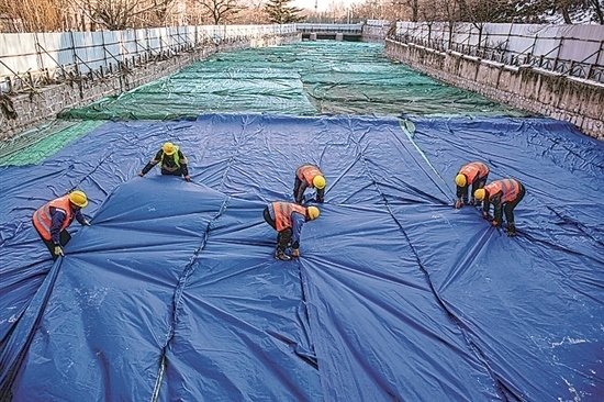 1月3日，房山區(qū)東風(fēng)街道，工人正在修復(fù)的河道內(nèi)給混凝土鋪設(shè)保溫布。