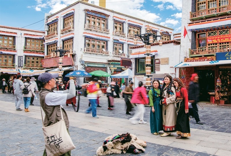 千年八廓街，見(jiàn)證民族團(tuán)結(jié)。2021年7月，習(xí)近平總書(shū)記來(lái)到位于西藏拉薩老城區(qū)的八廓街，感慨地說(shuō)：“千年八廓街，是我們各民族建起來(lái)的八廓街。各民族文化在這里交流交往交融，我們中華民族的大家庭在這里其樂(lè)融融?！眻D為2023年6月13日，游客身著藏裝在八廓街拍照留念。 新華社記者 姜帆/攝