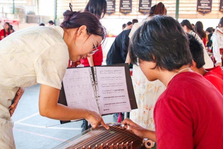 志愿者教師指導(dǎo)學(xué)生彈奏古箏?；顒又鬓k方供圖