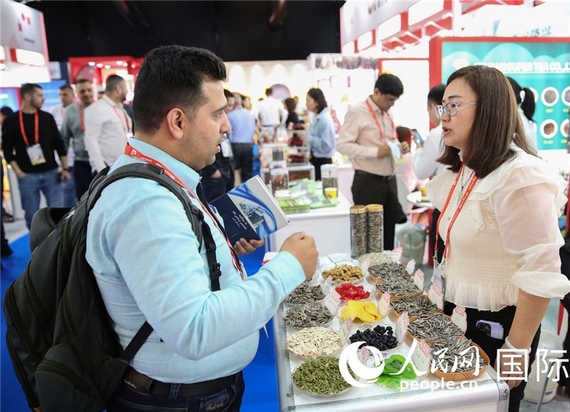 圖為一家中國干果參展企業(yè)代表與采購商洽談。人民網(wǎng) 塔里克·易卜拉欣攝