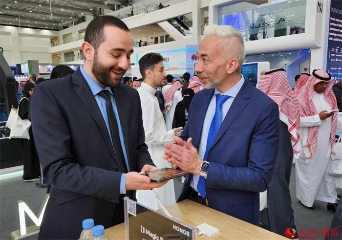 兩名觀眾在榮耀手機展臺前交流。人民網(wǎng)記者 管克江攝