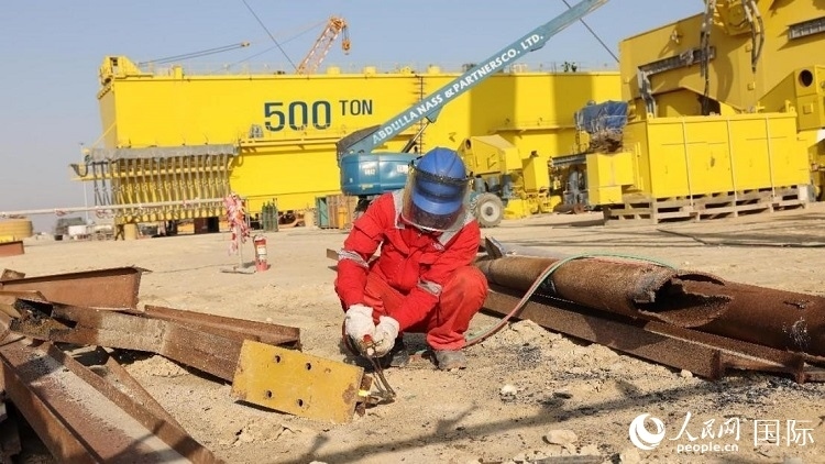 工人正在龍門吊吊裝現(xiàn)場切割金屬件。人民網(wǎng)記者管克江攝