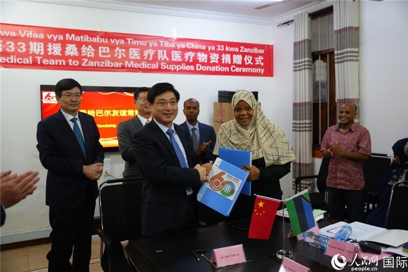 江蘇省蘇北人民醫(yī)院黨委書記束余聲與桑衛(wèi)生部首席秘書哈比巴交換捐贈書。中國援桑醫(yī)療隊供圖