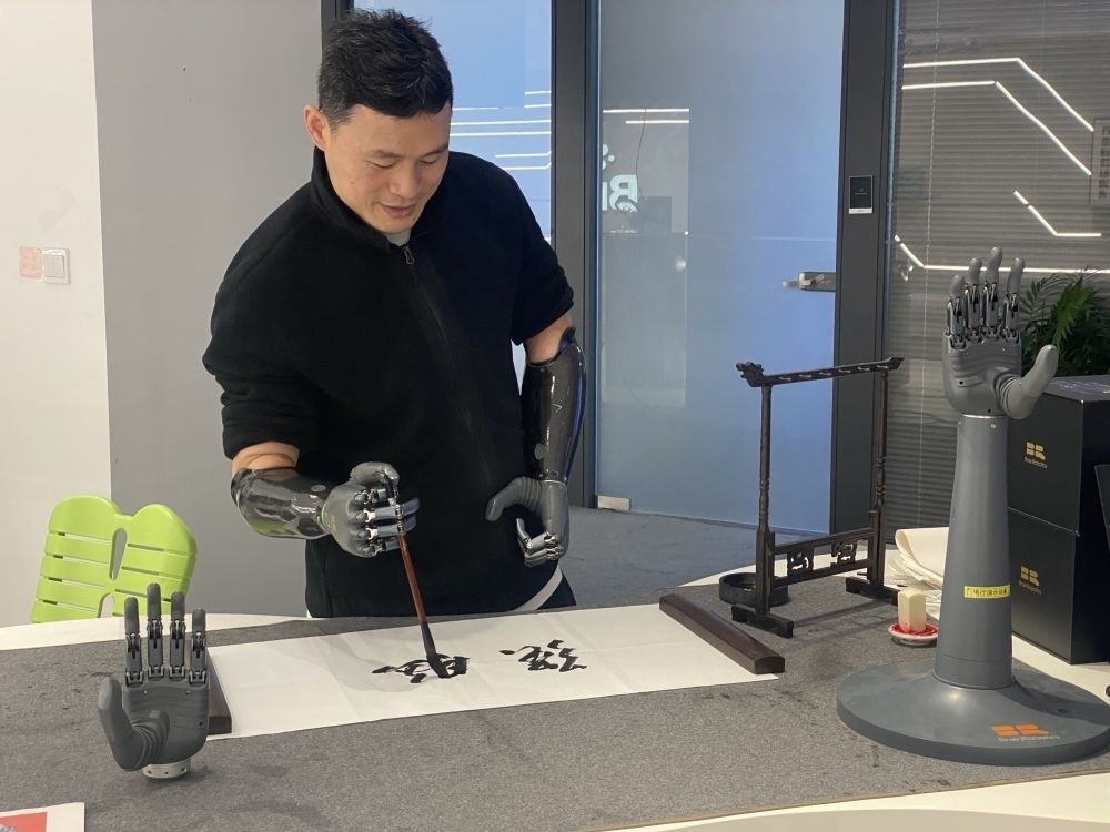 2024年3月29日，在浙江強(qiáng)腦科技有限公司展廳內(nèi)，失去雙手的產(chǎn)品體驗(yàn)官倪敏成依靠智能仿生手寫毛筆字。新華社記者 魏一駿 攝