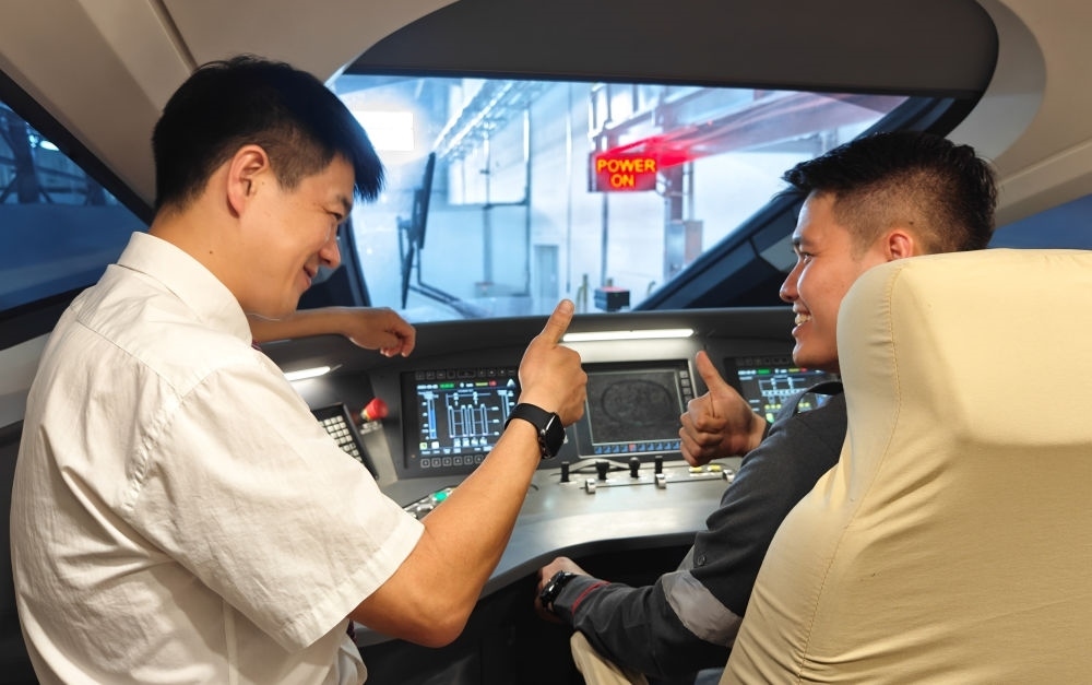 2023年8月25日，在印度尼西亞萬隆的雅萬高鐵德卡魯爾動車所內(nèi)，中國師傅穆振（左）向印尼火車司機(jī)塞蒂亞萬講解動車組出庫前的上電作業(yè)。新華社記者 徐欽 攝