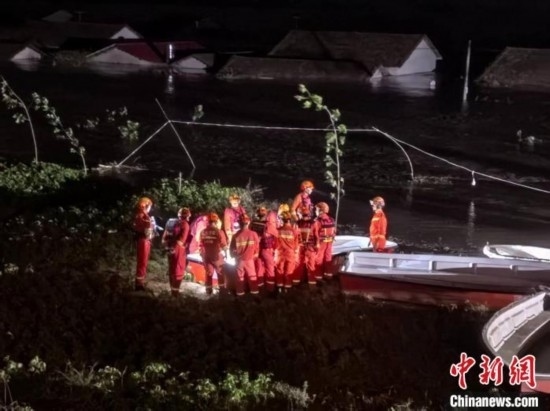  7月6日凌晨3時，在湖南岳陽華容縣團洲垸洞庭湖一線堤防，救援人員剛剛完成一次救援任務，遠處是被淹的民房。中新社記者 白祖偕 攝