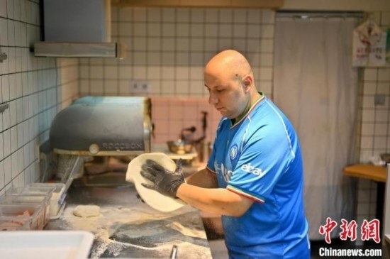 近日，韋榮耀在自家披薩小店內(nèi)忙活。俞靖 攝