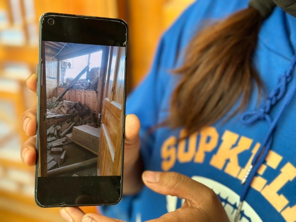 圖為7月17日拉毛東智在手機(jī)上找出地震后房屋受損的照片。新華社記者 張子琪 攝