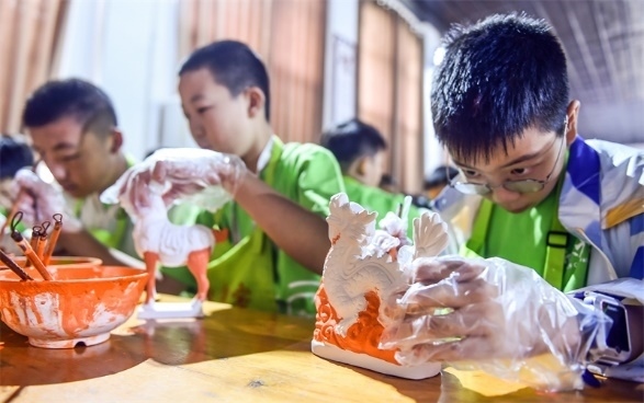 小朋友們?cè)诼尻柺忻辖騾^(qū)朝陽鎮(zhèn)南石山村體驗(yàn)唐三彩素胎施釉技藝。圖片來源：視覺中國(guó)