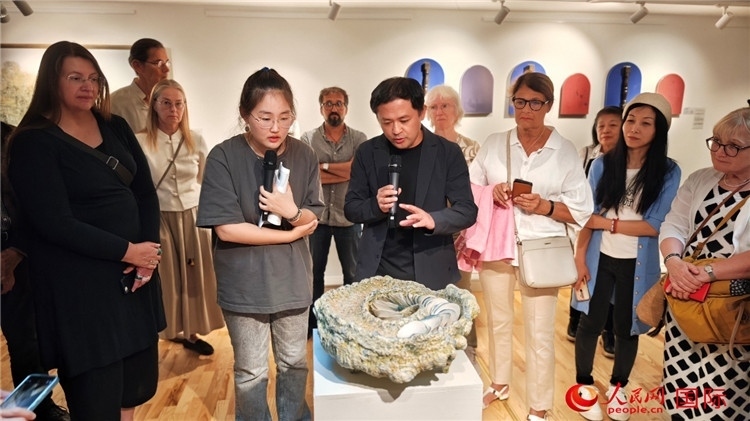 參展人、景德鎮(zhèn)陶瓷大學(xué)設(shè)計(jì)藝術(shù)學(xué)院副院長(zhǎng)余劍峰（中）向來賓介紹參展作品。人民網(wǎng)記者 殷淼攝