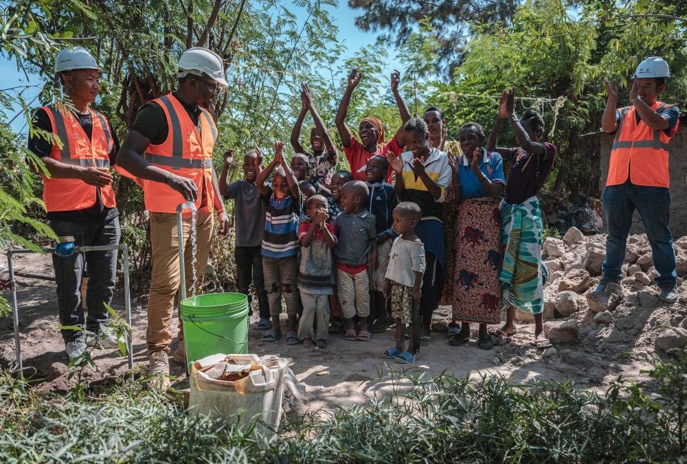 2023年6月13日，在坦桑尼亞姆萬扎省米松圭，工作人員接通水管后贏得當(dāng)?shù)鼐用窆恼茪g呼。新華社記者 王冠森 攝