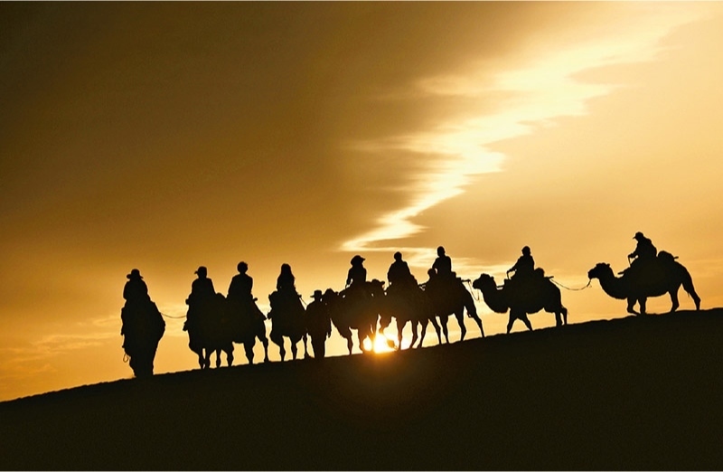 新時代以來，文化和旅游深度融合發(fā)展體制機(jī)制不斷健全，成功走出了一條獨(dú)具特色的中國旅游發(fā)展之路。圖為2024年9月1日清晨，游客在甘肅省敦煌市鳴沙山月牙泉景區(qū)乘騎駱駝，欣賞大漠風(fēng)光，體驗(yàn)絲路風(fēng)情。 新華社發(fā) 張曉亮/攝