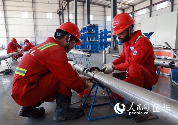 中伊員工共同在檢修鉆井設(shè)備。人民網(wǎng)記者管克江攝