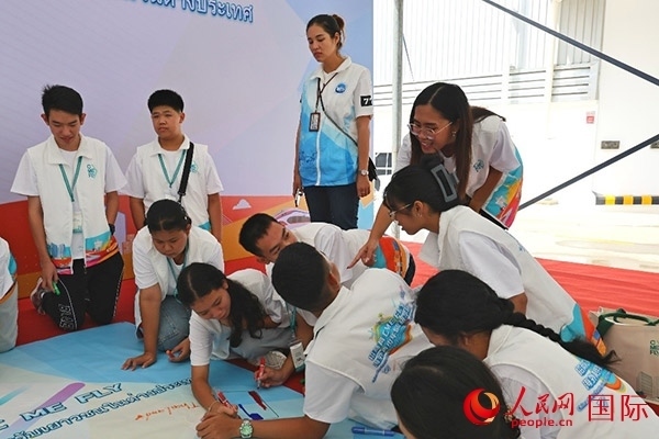 泰國(guó)學(xué)生在開營(yíng)儀式展板上繪制圖案。人民網(wǎng)記者 白元琪攝