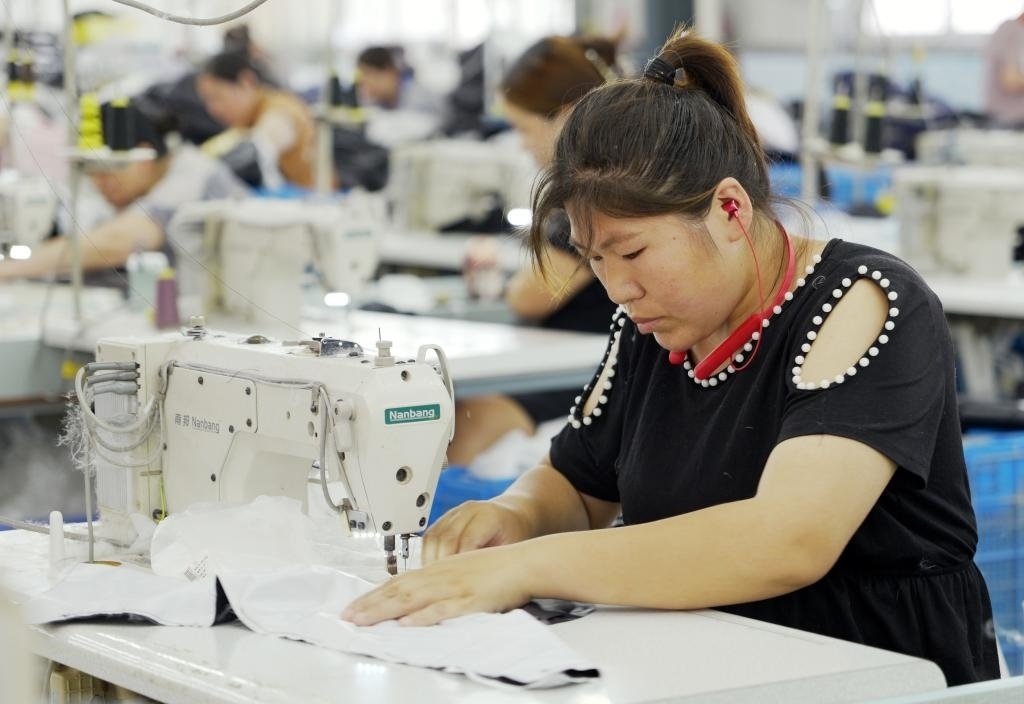 5月20日，村民在李寨村服裝加工廠內(nèi)忙碌。河南省周口市沈丘縣馮營鎮(zhèn)李寨村地處豫東平原。近年來，乘著脫貧攻堅與鄉(xiāng)村振興政策的東風，李寨村積極探索產(chǎn)業(yè)發(fā)展模式，通過“龍頭企業(yè)+村集體經(jīng)濟+農(nóng)戶”的方式，逐漸發(fā)展形成肉牛養(yǎng)殖、設(shè)施農(nóng)業(yè)、服裝加工、康養(yǎng)民宿等產(chǎn)業(yè)，以產(chǎn)業(yè)振興助力鄉(xiāng)村振興。新華社記者 李嘉南 攝