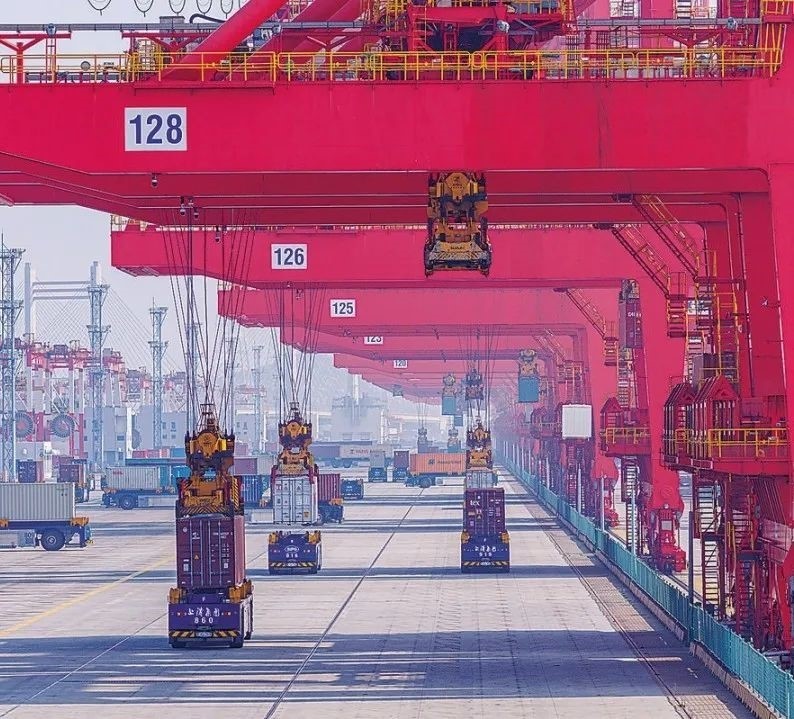 共建“一帶一路”國家在工作制度對接、技術(shù)標準協(xié)調(diào)、檢驗結(jié)果互認等方面強化合作、統(tǒng)一標準，貿(mào)易自由化便利化水平不斷提升。上海洋山港海關(guān)對接共建國家進出口貨物相關(guān)標準，推動通關(guān)一體化方式申報，提升通關(guān)效率。圖為無人駕駛的全自動導引車在洋山港穿梭往來，搬運集裝箱。王初 攝