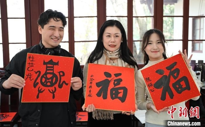 1月20日，外籍留學生和西泠印社社員李硯(中)展示各自創(chuàng)作的福貼。當日，來自巴西、馬來西亞、加納、哈薩克斯坦的外籍留學生在浙江杭州西泠印社體驗福貼、春聯(lián)和篆刻，感受古老的中國傳統(tǒng)文化。中新社記者 王剛 攝