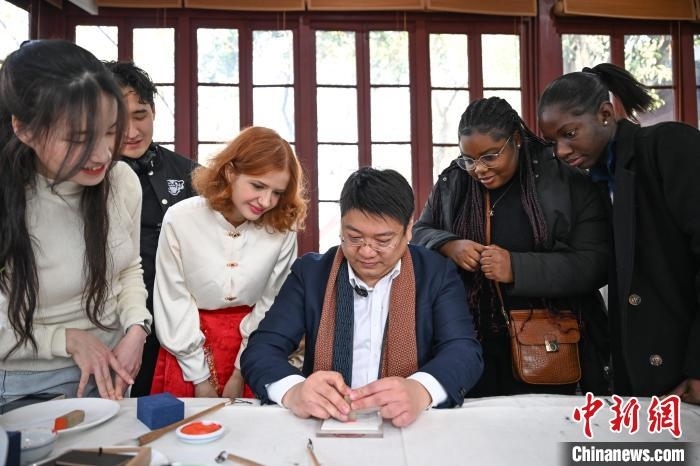 1月20日，篆刻家王臻向外籍留學生展示篆刻印章。當日，來自巴西、馬來西亞、加納、哈薩克斯坦的外籍留學生在浙江杭州西泠印社體驗福貼、春聯(lián)和篆刻，感受古老的中國傳統(tǒng)文化。中新社記者 王剛 攝