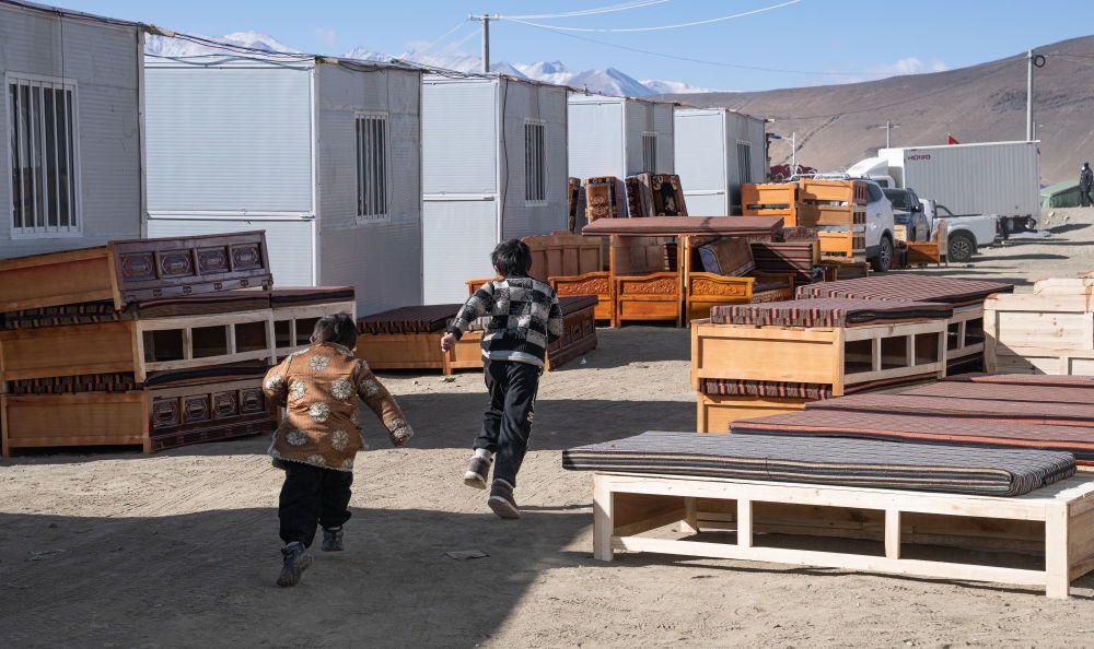 2025年1月13日，在定日縣嘎旦村，兩個(gè)孩子在剛運(yùn)來的兩排藏床間奔跑。新華社記者丁增尼達(dá) 攝