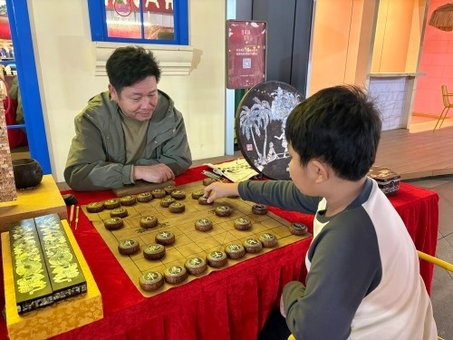 柯秋楓與市民下椰雕象棋。人民網(wǎng) 陳葉欣攝