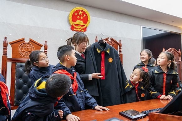 圖②：干警向同學(xué)們介紹法袍。