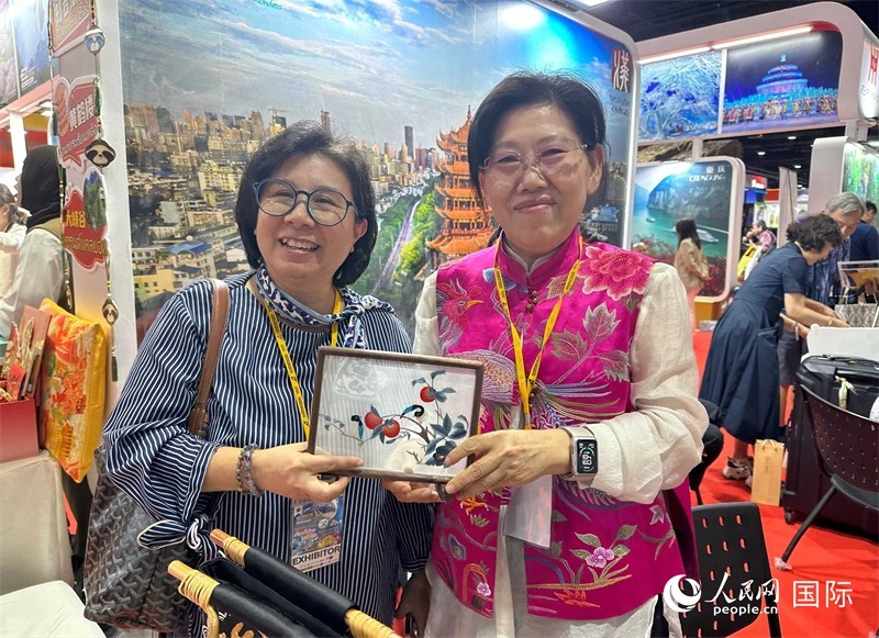 中國“大冶刺繡”傳承人劉小紅（右）參加泰國國際旅游展，向觀眾介紹中國非遺刺繡針法。人民網(wǎng)記者 簡承淵攝