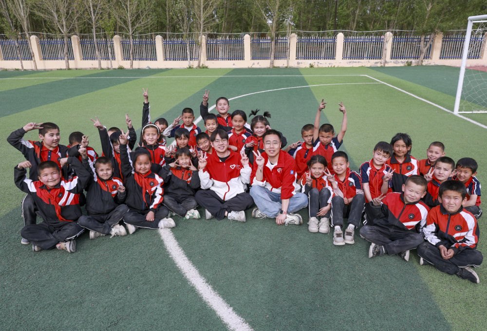 4月23日，在新疆克州阿圖什市哈拉峻鄉(xiāng)謝依特小學(xué)，支教教師王俊文（中左）、李軻凡（中右）和學(xué)生在一起。