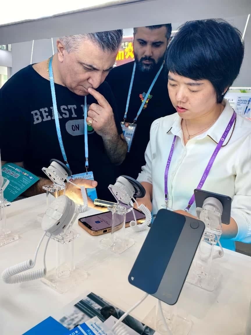 展臺工作人員向外商展示“AI TOP翻譯終端”。圖片來源：受訪者提供